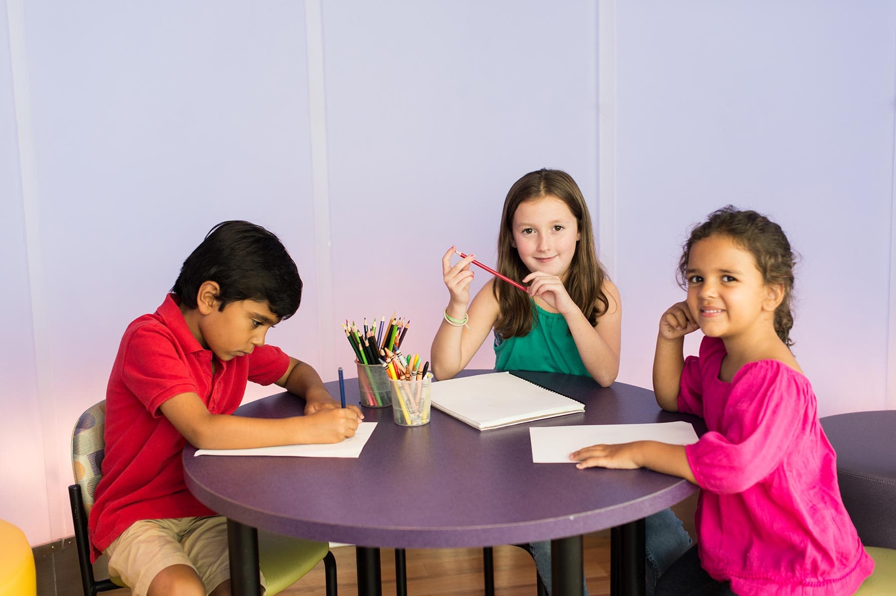 Three children draw at a table after they've finished their ultrasound exam