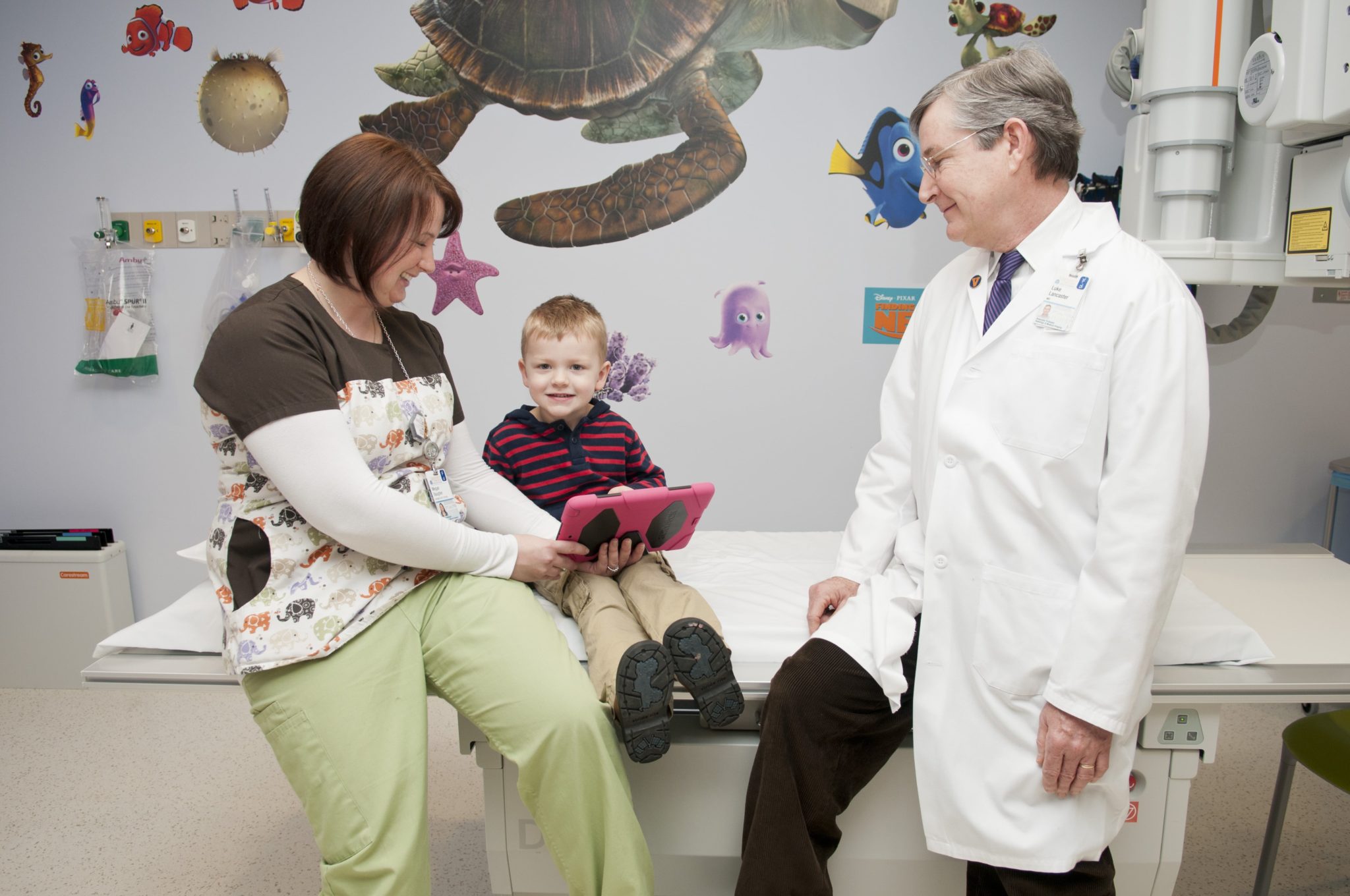 A male doctor and female nurse talk with a boy in a waiting room in the UVA pediatric radiology department