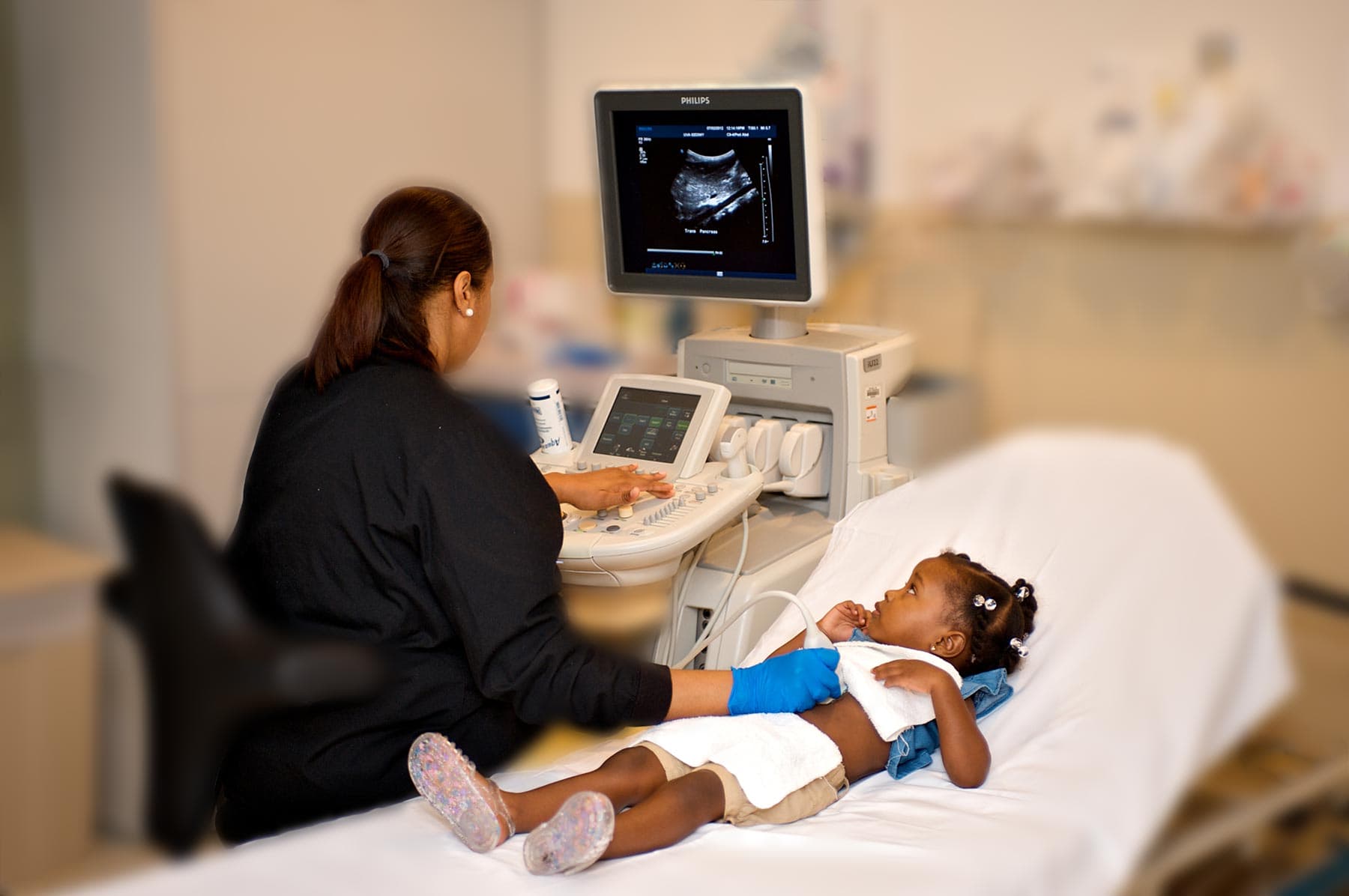 A radiologist gives a young girl an ultrasound as the girl looks at the monitor
