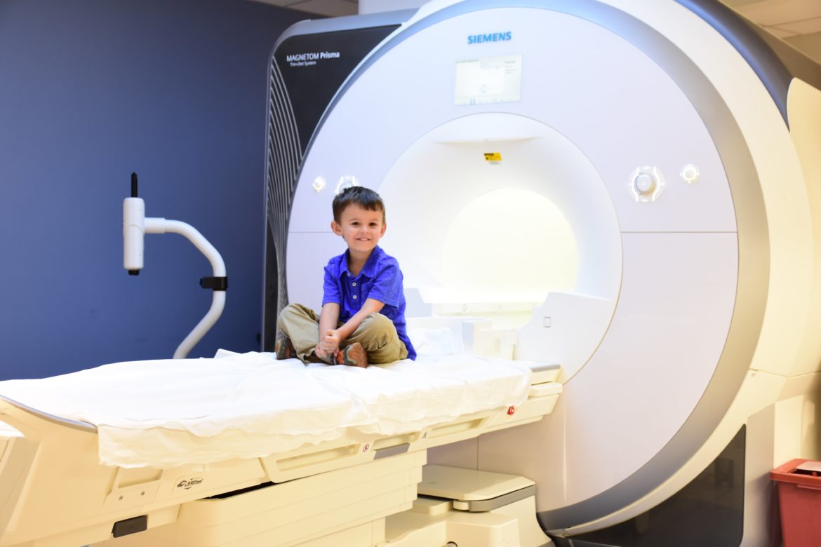A boy sits in front of an MRI machine before his exam
