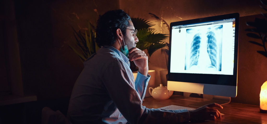 a radiologist examines a chest x-ray on a computer screen in a darkened room